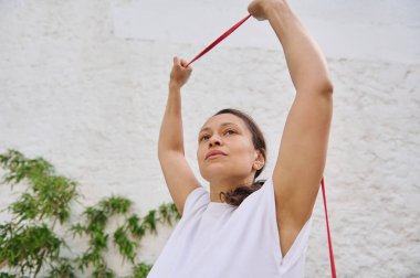 Odaklanmış kadın dışarıda direnç bandı egzersizi yapıyor, fitness, güç ve kararlılığı vurguluyor..