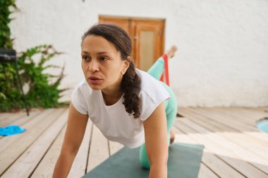 Açık havada yoga yapan aktif giyimli bir kadın denge ve konsantrasyona odaklanıyor. Huzurlu ortam rahatlamayı ve farkındalığı arttırır..