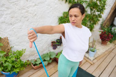 Bir kadın bahçede bir direniş grubuyla çalışıyor. Güç, odaklanma ve fitness yaşam tarzı gösteriyor..