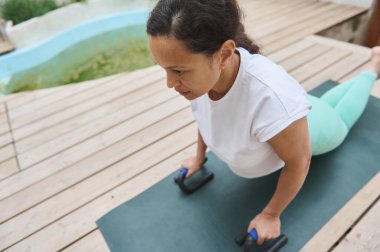 Ahşap bir güvertede yoga yapan, kobra pozu veren bir kadın. Açık havada, rahatlama, zindelik ve farkındalığı vurguluyor..