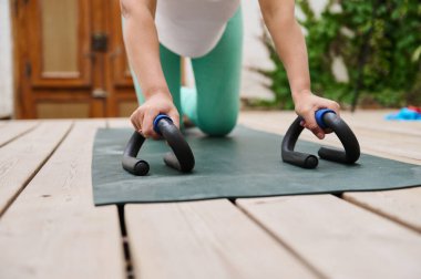 Dışarıdaki yoga minderinde şınav çeken bir kadının güç ve zindeliğe odaklandığı yakın plan çekimleri..