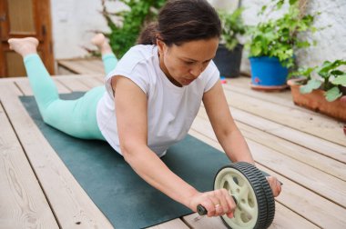 Yoga minderiyle egzersiz yapan odaklanmış bir kadın. Bitkilerle çevrili, sağlıklı ve sağlıklı..
