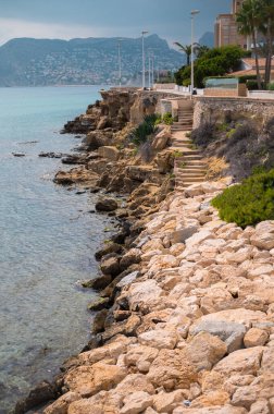 Okyanus manzaralı kayalık kıyılarla çevrili manzaralı, bulutlu gökyüzünün altında, sakin bir sahil kenarında yer alan manzaralı bir sahil yolu..