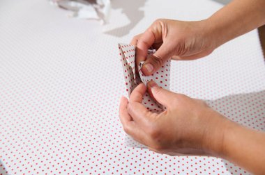 Kırmızı benekli beyaz kağıtlarla süslenmiş bir hediyeyi dikkatlice saran eller şenlikli ruhu ve detaylara olan ilgiyi somutlaştırıyor..