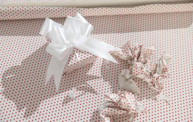 Güzel paketlenmiş bir hediye kutusu, beyaz kurdeleli benekli ambalaj kağıdı, zarafet saçıyor ve kutlama yapıyor..