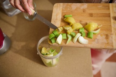 Günümüz mutfağında bulaşık makinesinin önünde diz çökmüş bir kadın bulaşık yıkıyor. Canlı kırmızı dolap, işlevsel ortama kontrastlık ve sıcaklık ekler.. 
