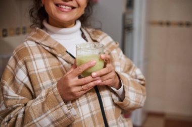 Günümüz mutfağında bulaşık makinesinin önünde diz çökmüş bir kadın bulaşık yıkıyor. Canlı kırmızı dolap, işlevsel ortama kontrastlık ve sıcaklık ekler.. 