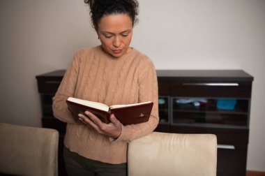 Ilık bir odada kitap okuyan bir kadın rahatlama ve odaklanma iletiyor. Günlük kıyafetleri ortama hoş bir hava katıyor..