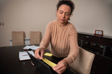 A woman organizes paperwork in a home office, creating a focused and productive environment. clipart