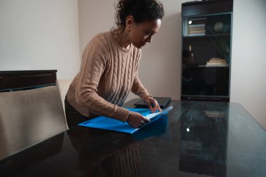 A woman is arranging paperwork on a modern office desk, showcasing a tidy and productive workspace environment. The image suggests organization and attention to detail. clipart