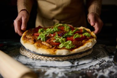 Taze fesleğenli ve olgun domatesli lezzetli bir ev yapımı pizza, yemeye hazır. Yemek meraklıları ve ev aşçıları için mükemmel bir akşam yemeği için ilham ya da yaratıcı bir mutfak deneyimi arayan.