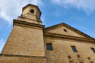 Detaylı mimari özelliklere sahip görkemli bir taş bina berrak mavi gökyüzüne karşı yükselir, tarihsel ve zamansız bir his sunar..