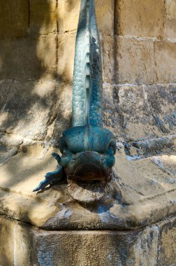Kırsal taştan bir duvarda gizemli mavi bir heykel, ilginç dokusunu ve detaylarını aydınlatıyor. Tarihi mimari ve efsanevi yaratıkların aşıkları için mükemmel..