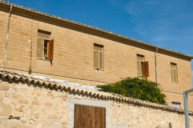 Açık ahşap kepenkleri olan büyüleyici tarihi bir bina, açık mavi gökyüzüne karşı güneşlenerek klasik mimari sergileniyor..