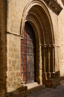 Tarihi mimari ve ortaçağ tasarım unsurlarının sergilendiği süslü ahşap kapılı güzel korunmuş bir taş kemer. Güneş ışığı desenli yüzeyde gölgeler bırakır ve eski cazibesini arttırır..
