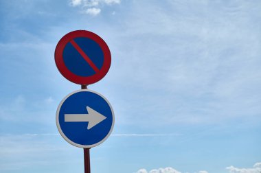 Açık bir günde iki trafik işaretine ve sağa dönüş yönüne izin verilmiyor. Canlı mavi gökyüzü ve kabarık bulutlar işaretlerle çarpıcı bir kontrastlık yaratır..