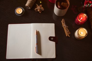 Açık bir defter, kalem, mum ve bir fincan kakao içeren davetkar bir çalışma düzeneği. Yaratıcı yazarlık veya günlük tutmak için mükemmel..