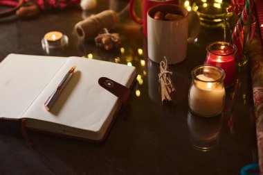 Bir günlük, sıcak ışıklar, mumlar ve rahat bir atmosferi taşıyan çay ile iç açıcı bir masa sahnesi..