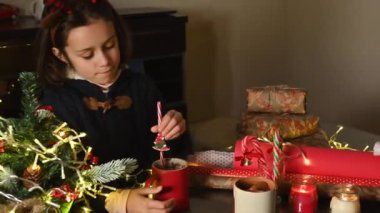 Noel süsleri ve Noel hediyeleriyle çevrili sıcak içeceği karıştıran genç kız, sıcak bir tatil ruhunu çağrıştırıyor..