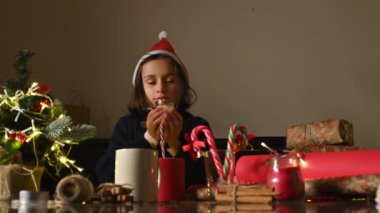 Noel Baba şapkası takan genç bir kız dekoratif el sanatlarından hoşlanıyor, rahat bir ortamda bayram havası yaratıyor..