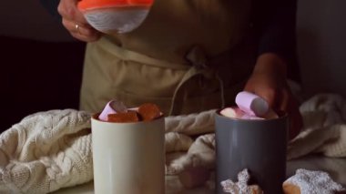 Marşmelov, kakao tozu ve şenlikli kurabiyelerle kaplı sıcak çikolata bardaklarıyla sıcak kış sahnesi..