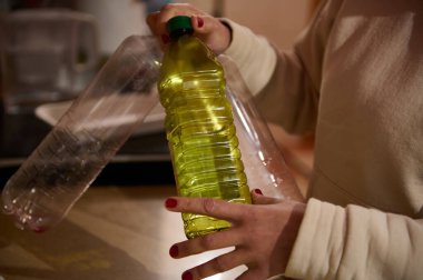 A close-up view of someone handling empty plastic bottles and one containing a yellow liquid clipart