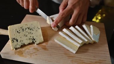 Brie ve küflü peynirin tahta kesme tahtasıyla dilimlendiği yakın plan bir çekim. Bu lezzetli peynir her parti ya da toplanma için mükemmeldir..