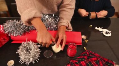 Dekorasyon ve süslemelerle yaratıcı Noel hazırlıklarının keyfini çıkaran bir aile. Samimi ve neşeli bir tatil anı. Takım çalışması ve evde benzersiz kişisel dokunuşları olan şenlikli bir ruh..