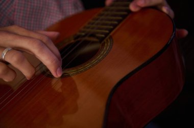 Close-up image of a person strumming a classical guitar, focusing on precise hand movements, evoking a sense of musical skill and passion for playing stringed instruments. clipart