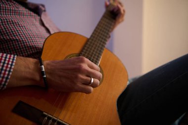 Close-up shot of an individual strumming an acoustic guitar while seated indoors, showcasing expression and skill in playing a string instrument, creating a warm and peaceful atmosphere. clipart