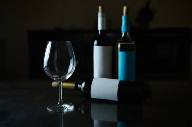 A wine glass accompanied by three wine bottles, creating a stylish and moody scene. clipart