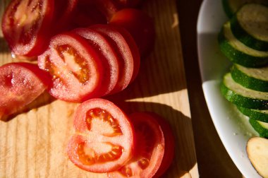 Taze dilimlenmiş domates ve kabak, canlı renkler ve detaylar sergiliyor. Yemek hazırlama kavramları ya da sağlıklı yaşam tarzı görselleri için mükemmel..