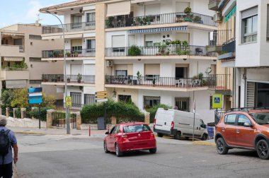 Urban scene showcasing a residential street surrounded by parked cars and residential buildings with balconies. Lush greenery adds vibrancy in the neighborhood. clipart