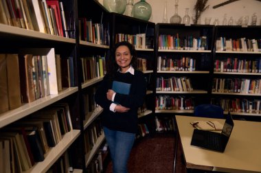 Bir kadın kütüphanede elinde bir kitapla, bilgi ve ilhamla mutlu bir şekilde durur..