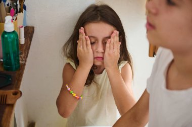 Genç bir kız banyoda yüzünü yıkıyor, günlük hijyen alışkanlıklarını vurguluyor..