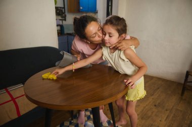 Bir anne ve kızının birlikte ev işleriyle meşgul olduğu yürek ısıtan bir an. Görüntü bağ kurmayı, takım çalışmasını ve sıcak ve sıcak bir ev içinde aile bağı kurmayı gösteriyor..