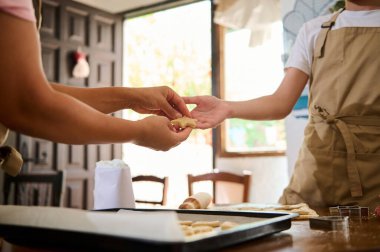 Two individuals are working together in a well-lit open kitchen preparing bakery goods. clipart