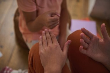 Kapalı alanda, ahşap döşeme ve sıcak renkli kıyafetlerle el hareketleriyle iletişim kuran iki insanın yakın çekim görüntüsü..