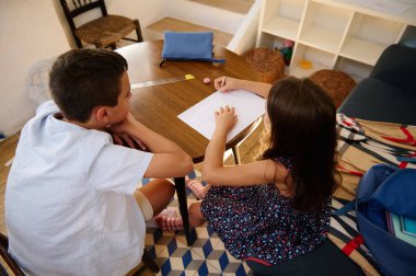 İki çocuk, ahşap bir masada, takım çalışmasını ve eğitimi destekleyen bir öğrenim görevinde işbirliği yapıyor..