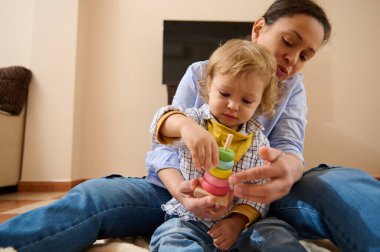 Anne, evde canlı bir eğitim oyuncağıyla oynarken bebeğiyle sevgi dolu bir şekilde ilişki kuruyor ve öğrenmeyi teşvik ediyor..
