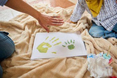 Yetişkin ve çocuk olarak yumuşak bir battaniyede yaratıcı bir aktivite. El izlerini boyamak, bağ, sanat ve eğlenceyi sembolize etmek..