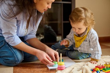 Yaratıcılıkla öğrenen, entelektüel gelişimi destekleyen ve eğitim faaliyetlerini besleyici bir ortamda birleştiren bir anne ve çocuk..