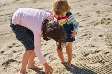Çocuklar el değmemiş bir plajda açık hava aktivitelerini seviyorlar. Sıcak güneşin altında oynarken kaynaşıyorlar..