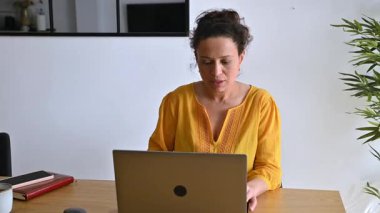 Evde dizüstü bilgisayarıyla çalışan bir kadın. Ofisinde odaklanmış ve üretken..