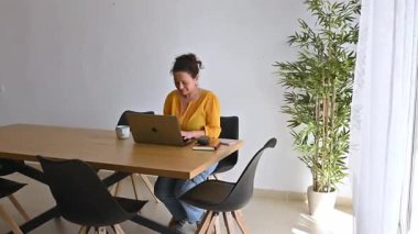 Evde dizüstü bilgisayarıyla çalışan bir kadın. Çalışma alanına odaklanmış ve üretken..