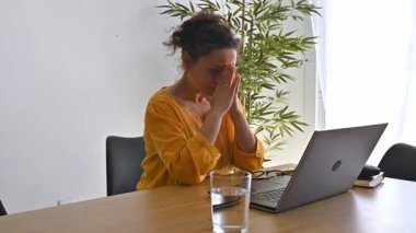 Evde bilgisayarla çalışan kadın stres, baş ağrısı, migren, tükenme ve hayal kırıklığı hissediyor..