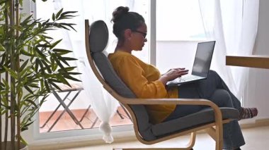 Uzaktan çalışan bir kadın, doğal ışıkla rahat bir çalışma alanının keyfini çıkarıyor..