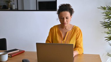 Huzurlu bir ofis ortamında dizüstü bilgisayarla uzaktan kumanda kullanan kendini işine adamış bir kadın. Modern, rahat bir iç mekanda dijital göçebe yaşam tarzının dengesini ve özgürlüğünü vurgulamak.