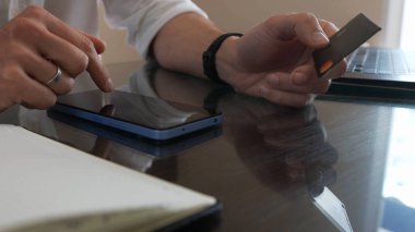 Akıllı telefon ve kredi kartıyla güvenli çevrimiçi işlemlere giren erkeklerin yakın çekimleri.