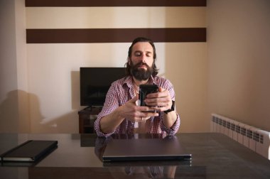 Günümüzün profesyoneli masasında oturmuş, verimliliği gösteren bir akıllı telefon kullanıyor. Önemli öğeler arasında bir dizüstü bilgisayar, bir defter ve minimalist ev ofisi kurulumu yer alıyor..